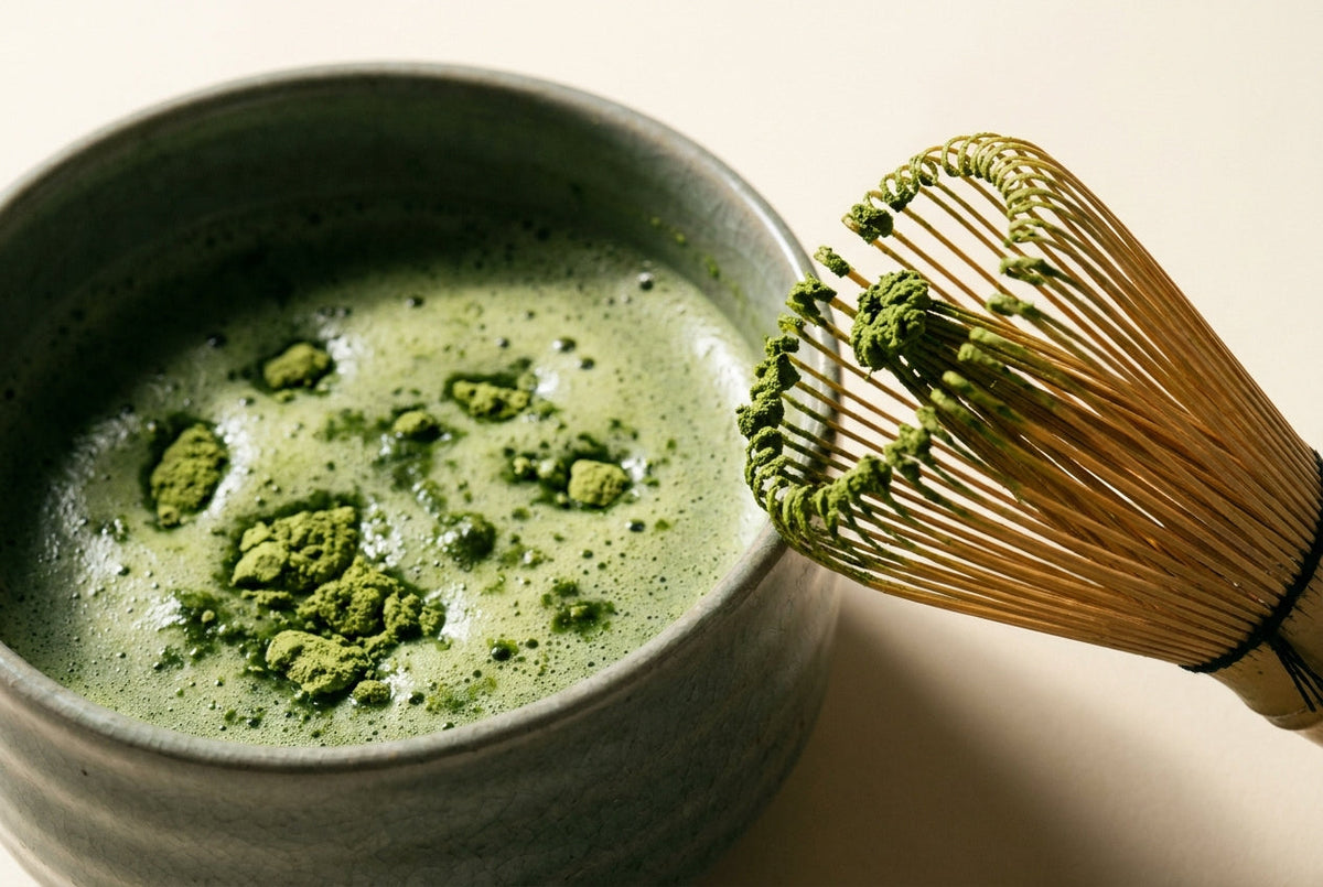Grumeaux de matcha en surface d'un bol avec chasen bambou Image